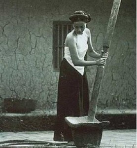 穀物を臼で砕いている女性