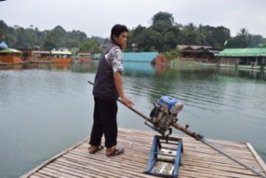 お兄さんが芝刈り機を水辺に向けている