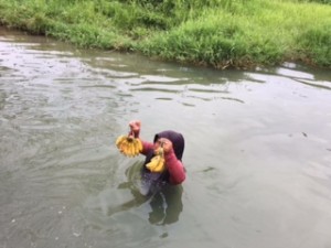 彼女はいかだに乗った客に商品を売りに来るおばあちゃん