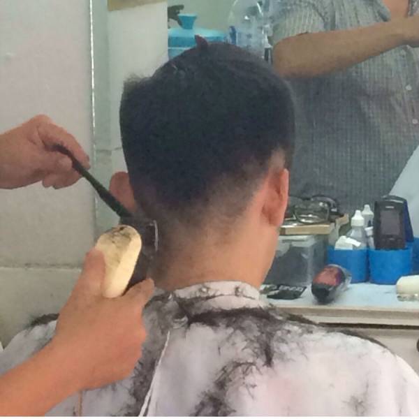 後ろの髪を刈られる金子