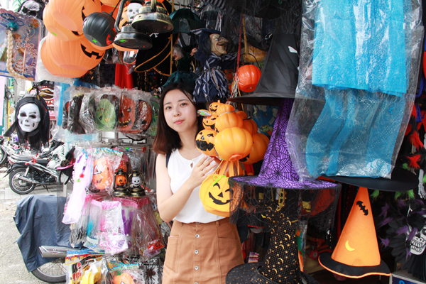 ハロウィングッズのお店から顔をのぞかせるあやな